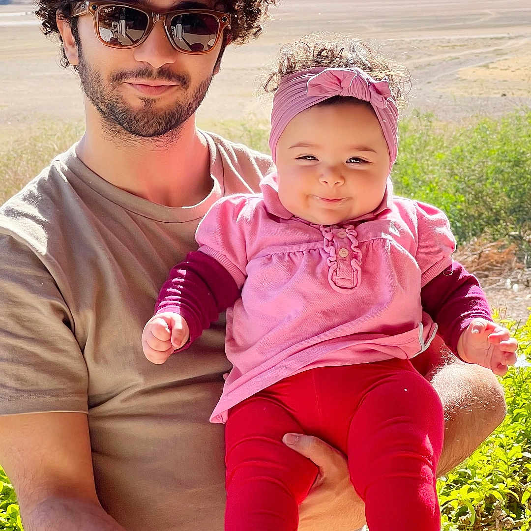 Louise Jasmine participe au concours pour gagner de l'argent avec cette photo : baby, baby_feet, child, curly_hair, family, greenery, happy, headband, holding, man, mountains, nature, outdoor, person, pink_clothing, portrait, red_pants, smile, sunglasses, sunlight