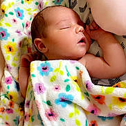 Madison is registered to the contest to win money with this photo: baby, newborn, sleeping, blanket, floral_pattern, infant, peaceful, soft_lighting, skin, arm, hand, closeup, indoors, resting, cute, child, person, toddler, cozy, comfort