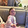 Valentina joined the competition — help win amazing prizes! baby, child, pajamas, pink, floral, couch, leather, pillow, home, indoor, person, face, hand, sitting, curious, clothing, bottle, decor, bag, plant