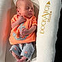 newborn, baby, sleeping, orange_shirt, anchor_design, striped_shorts, baby_lounger, dockatot, deluxe, cushion, infant, peaceful, soft_light, relaxing, indoor, clothing, footwear, person, portrait, sleep