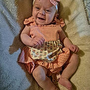 Addilyn is registered to the contest to win money with this photo: baby, infant, smiling, girl, headband, bow, dress, pink, patterned_clothing, blanket, cozy, cute, happy, lying_down, skin, small_hands, small_feet, indoors, child, portrait