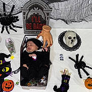 Celine joined the competition — help win amazing prizes! baby, black_clothing, box, child, costume, cute, decorations, fake_hand, festive, halloween, holiday, holiday_theme, indoor, pumpkin, skull, sleeping, spiders, table, tombstone, toy