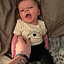 Lynette is registered to the contest to win money with this photo: baby, infant, person, hand, tattoo, wristband, clothing, onesie, bed, blanket, smiling, cute, happy, skin, footwear, socks, lying_down, indoor, cozy, affection