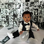 Kyleon is registered to the contest to win money with this photo: baby, tuxedo, balloon, black_and_white, portrait, child, infant, cute, formal_wear, sitting, photography, background, collage, monochrome, expression, face, clothing, indoor, person, young