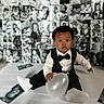 baby, tuxedo, balloon, black_and_white, portrait, child, infant, cute, formal_wear, sitting, photography, background, collage, monochrome, expression, face, clothing, indoor, person, young