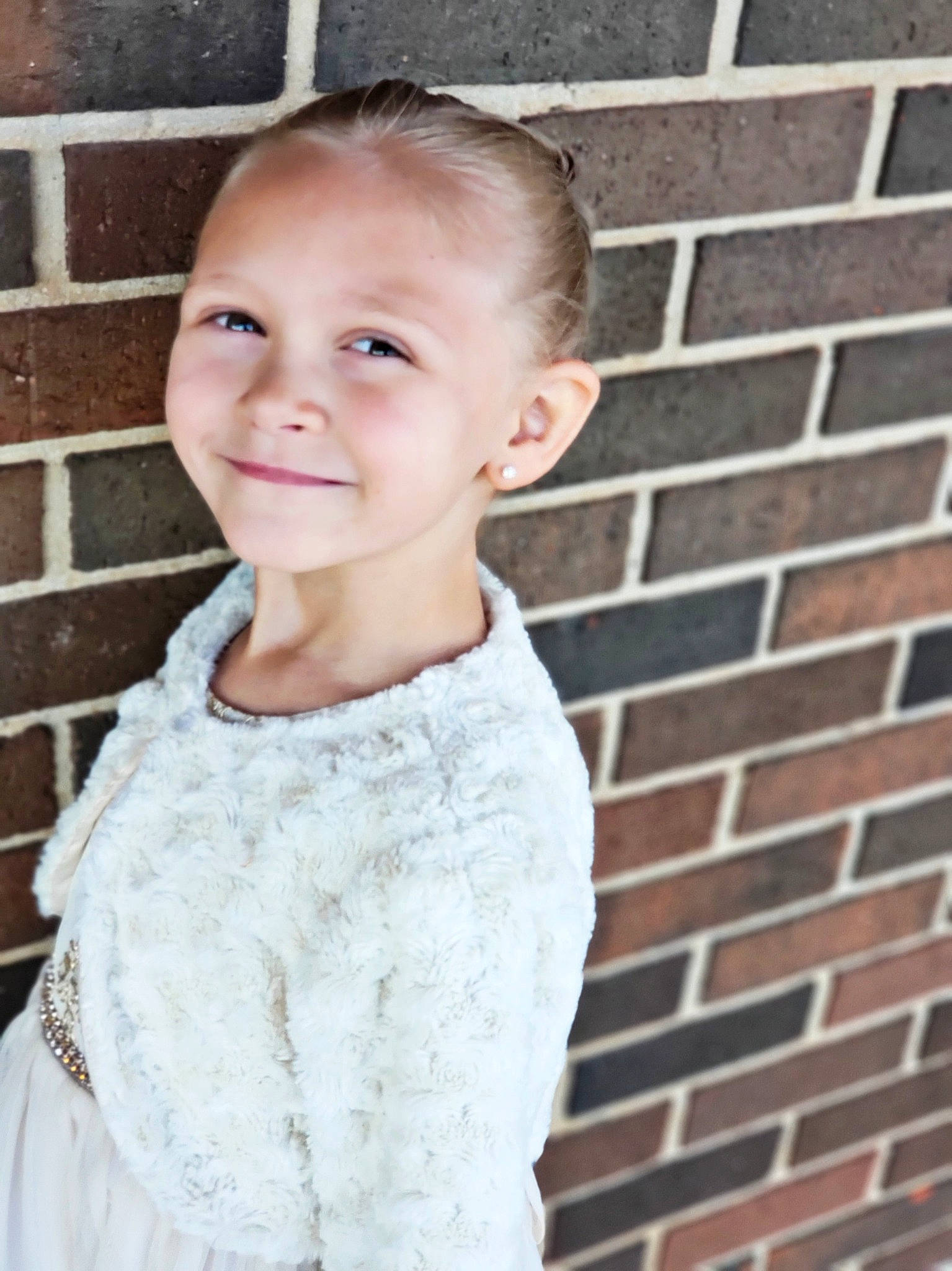 Braylee is registered to the contest to win money with this photo: baby_toddler_clothing, brick, brickwork, building_material, child, child_model, day_dress, ear, embellishment, hair, hair_accessory, iris, joy, mortar, neck, person, portrait_photography, sleeve, standing, toddler