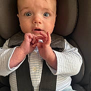 Harrison is registered to the contest to win money with this photo: baby, infant, car_seat, child, blue_eyes, hands, clothing, straps, safety, cute, portrait, young_child, face, expression, seated, indoor, closeup, person, apparel, soft_light