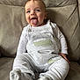 Harrison joined the competition — help win amazing prizes! baby, tongue_out, smiling, overalls, socks, couch, indoor, child, cute, happy, infant, person, clothing, seated, playful, young_child, face, expression, comfortable, home