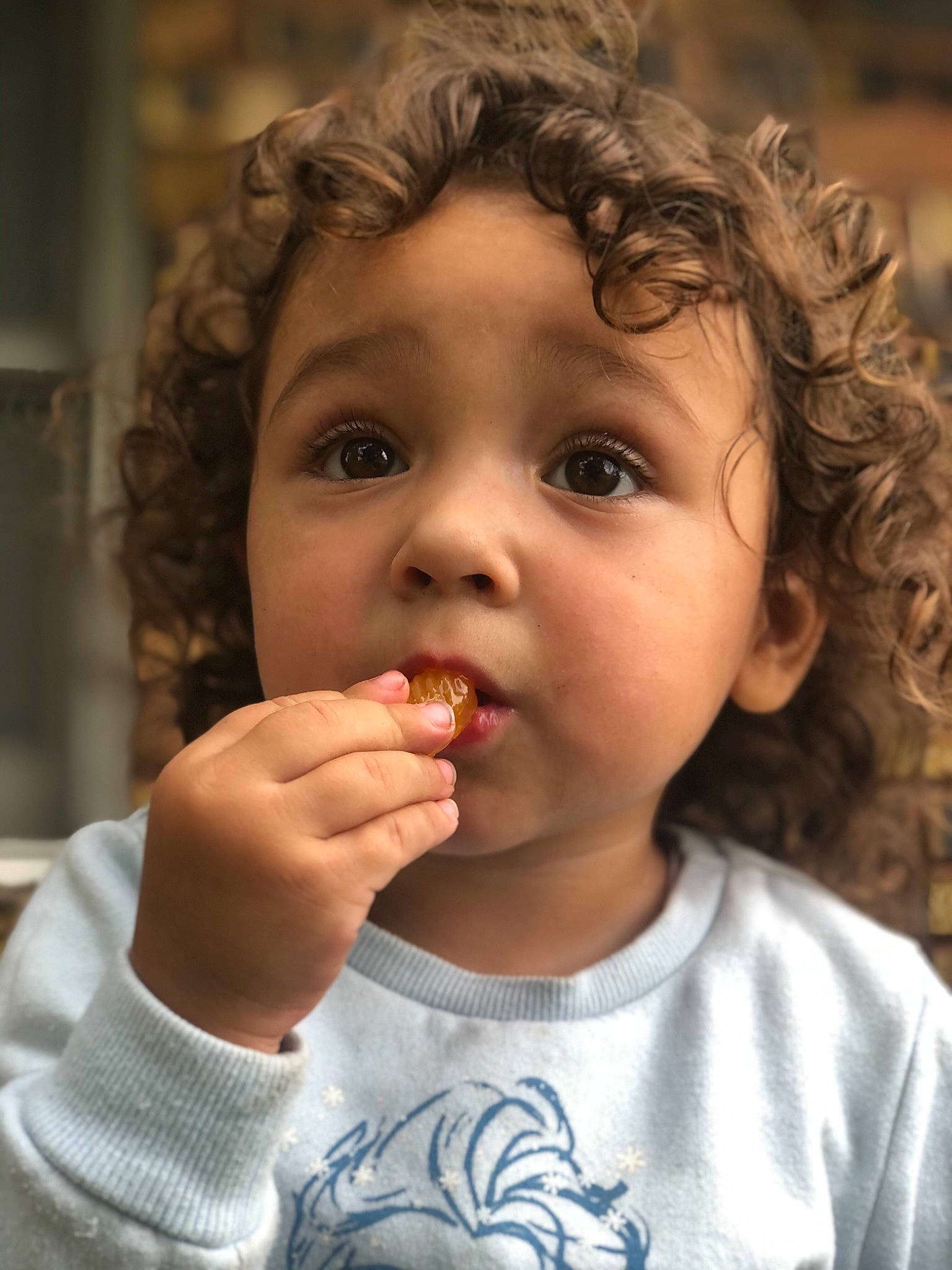Aliza is registered to the contest to win money with this photo: baby, baby_playing_with_food, baby_toddler_clothing, biting, brown_hair, cheek, child, chin, eating, eye, face, food_craving, lip, nose, person, ringlet, taste, toddler