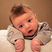 Gerald joined the competition — help win amazing prizes! baby, infant, child, portrait, closeup, lying_down, wide_eyed, surprised, smiling, face, hands, fingers, brown_hair, sweater, clothing, blanket, soft_texture, studio, warm_lighting, indoors