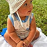 baby, child, hat, striped_hat, contact_lens_case, outdoor, grass, towel, sitting, curious, cute, summer, sun_hat, infant, portrait, cross_legged, baby_clothes, close_up, daylight, nature