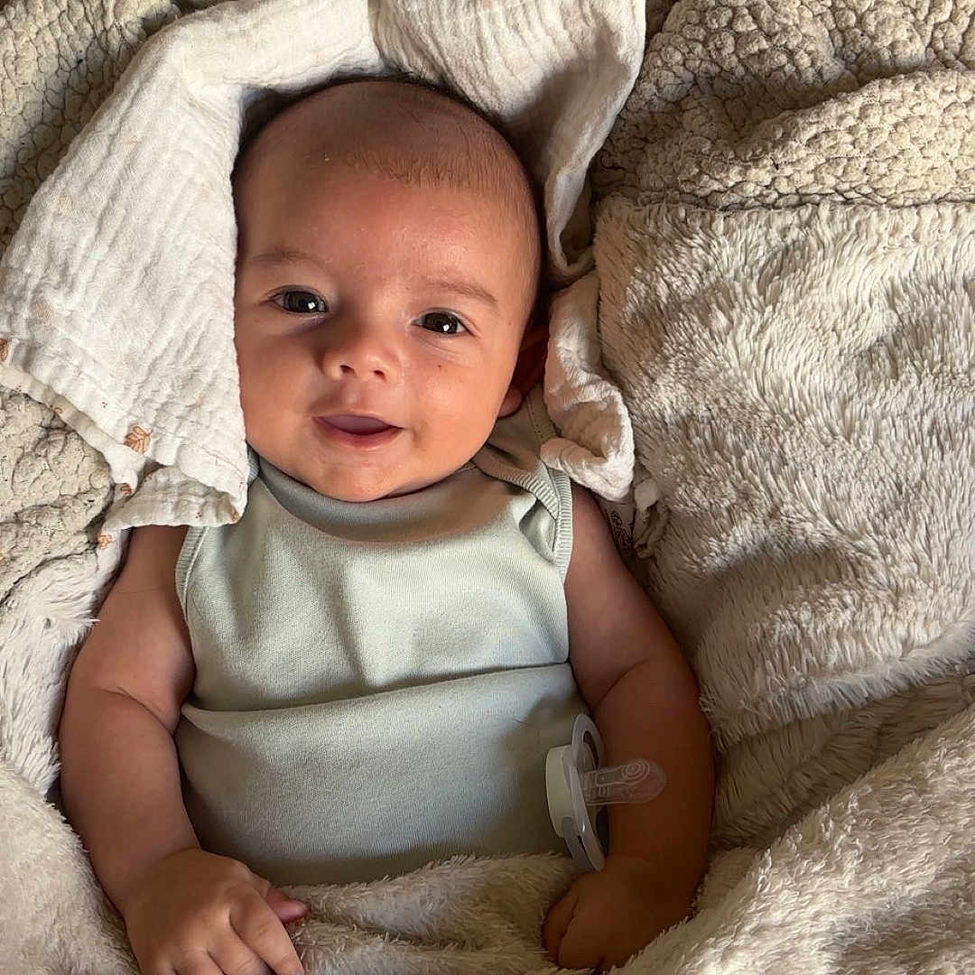 Aaron participe au concours pour gagner de l'argent avec cette photo : baby, bed, blanket, child, comfort, cozy, cute, fabric, face, happy, indoors, infant, pacifier, person, sleepwear, smile, soft, texture, warm, wrapped