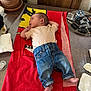 baby, infant, towel, clothing, jeans, shirt, wooden_surface, cactus, plant, keys, table, footwear, pacifier, diaper, baby_essentials, indoor, casual, relaxed, person, newborn