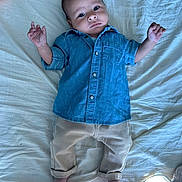 Joud participe au concours pour gagner de l'argent avec cette photo : baby, infant, denim_shirt, beige_pants, bed, white_bedspread, barefoot, curious_expression, lying_down, indoors, child, person, clothing, casual_wear, small_hands, small_feet, portrait, relaxing, cute, young