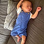 baby, sleeping, blue_overalls, couch, pillow, arm_stretched, barefoot, infant, relaxed, indoors, child, face, peaceful, rest, comfort, toddler, clothing, furniture, home, portrait