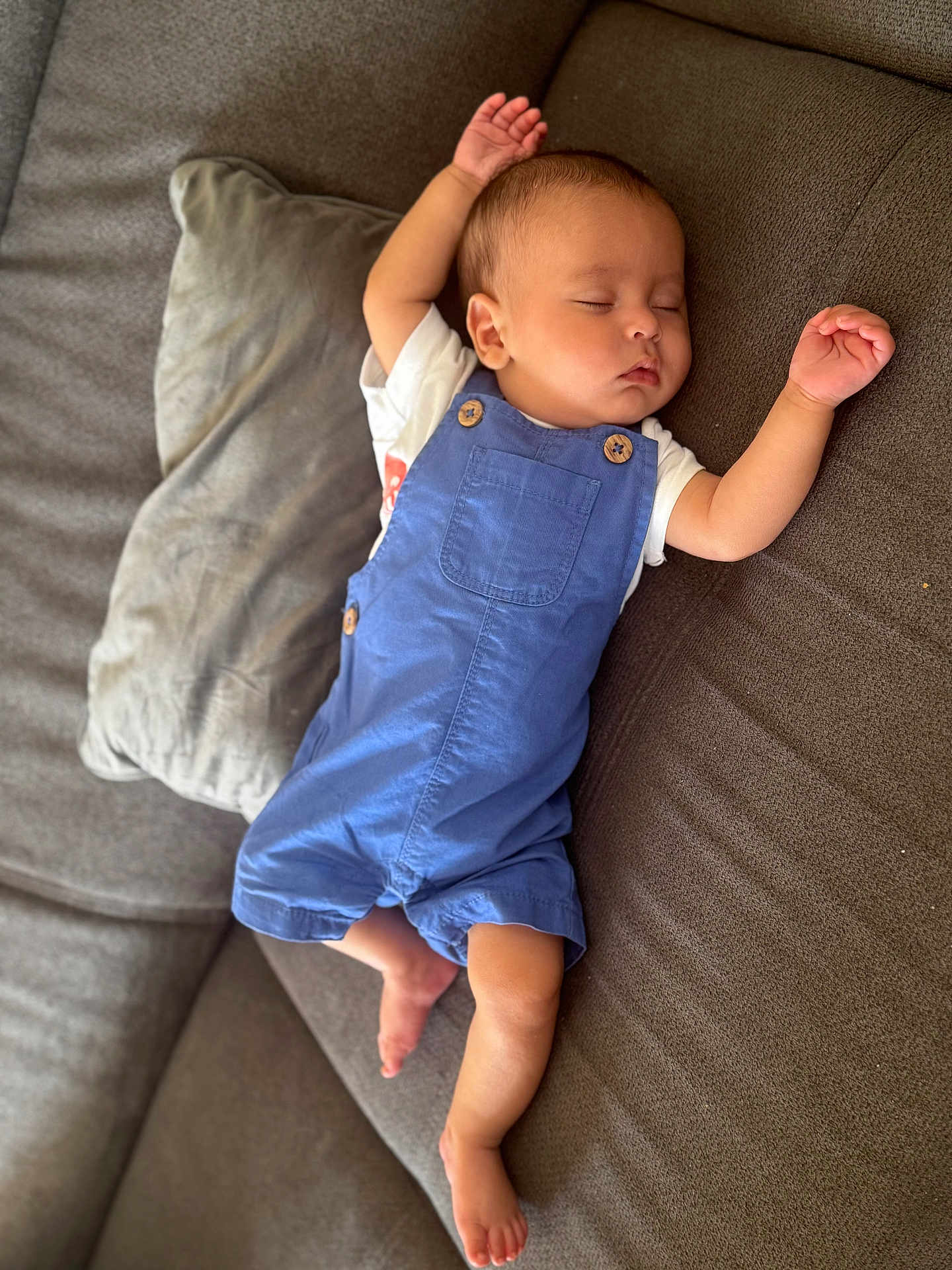 Joud a rejoint le concours — aidez-le/la à gagner de superbes lots ! baby, sleeping, blue_overalls, couch, pillow, arm_stretched, barefoot, infant, relaxed, indoors, child, face, peaceful, rest, comfort, toddler, clothing, furniture, home, portrait