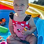 toddler, child, smiling, inflatable_pool, toy, water, summer, outdoor, sunlight, play, baby, sitting, cute, red_swimsuit, black_ruffles, happy, skin, foot, arm, face