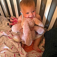 Sadie is registered to the contest to win money with this photo: baby, child, crib, toy, plush, bunny, blanket, smile, happy, indoor, person, cute, soft, furniture, infant, toddler, baby_clothing, colorful, comfort, playful