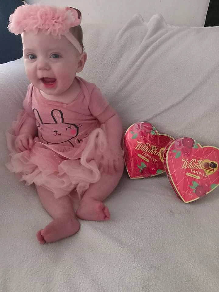Lainey is registered to the contest to win money with this photo: arm, baby, baby_toddler_clothing, clothing, comfort, foot, happy, head, headwear, human_body, human_leg, knee, leg, person, pink, sitting, skin, sleeve, smile, sock