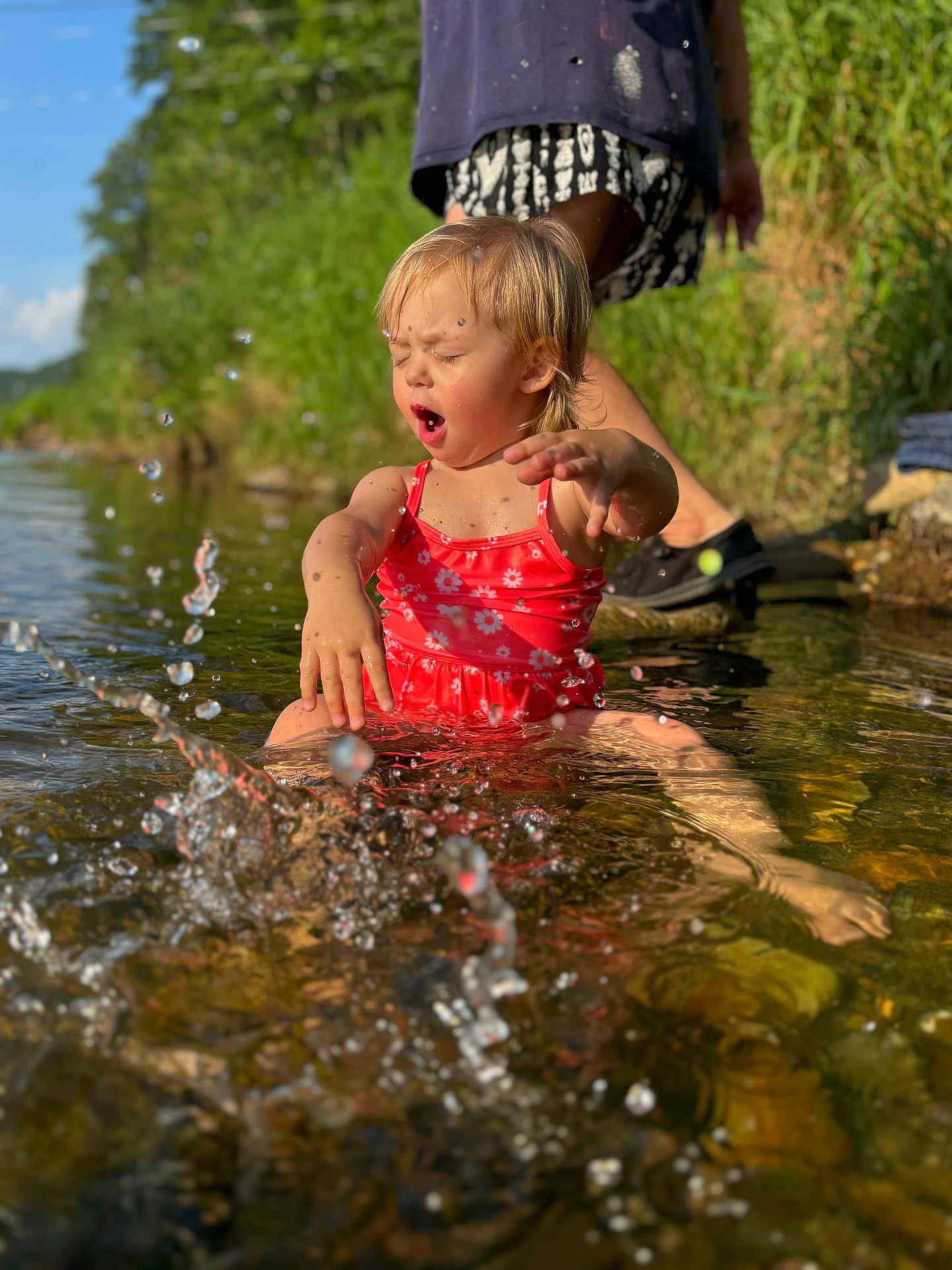 Dayna is registered to the contest to win money with this photo: adult, barefoot, child, creek, daytime, fun, grass, happy, nature, outdoor, person, play, river, splashing, summer, sunlight, swimsuit, toddler, water, water_droplets