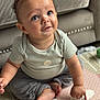 baby, child, blue_eyes, curly_hair, pointing, play_mat, couch, smiling, indoors, sitting, clothing, cute, expression, hand, foot, face, person, cozy, home, curious