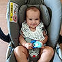 baby, car_seat, child, child_safety, cute, face, floor, foot, hands, happy, head, indoor, infant, lace_collar, legs, seatbelt, sitting, smiling, toy, white_clothing
