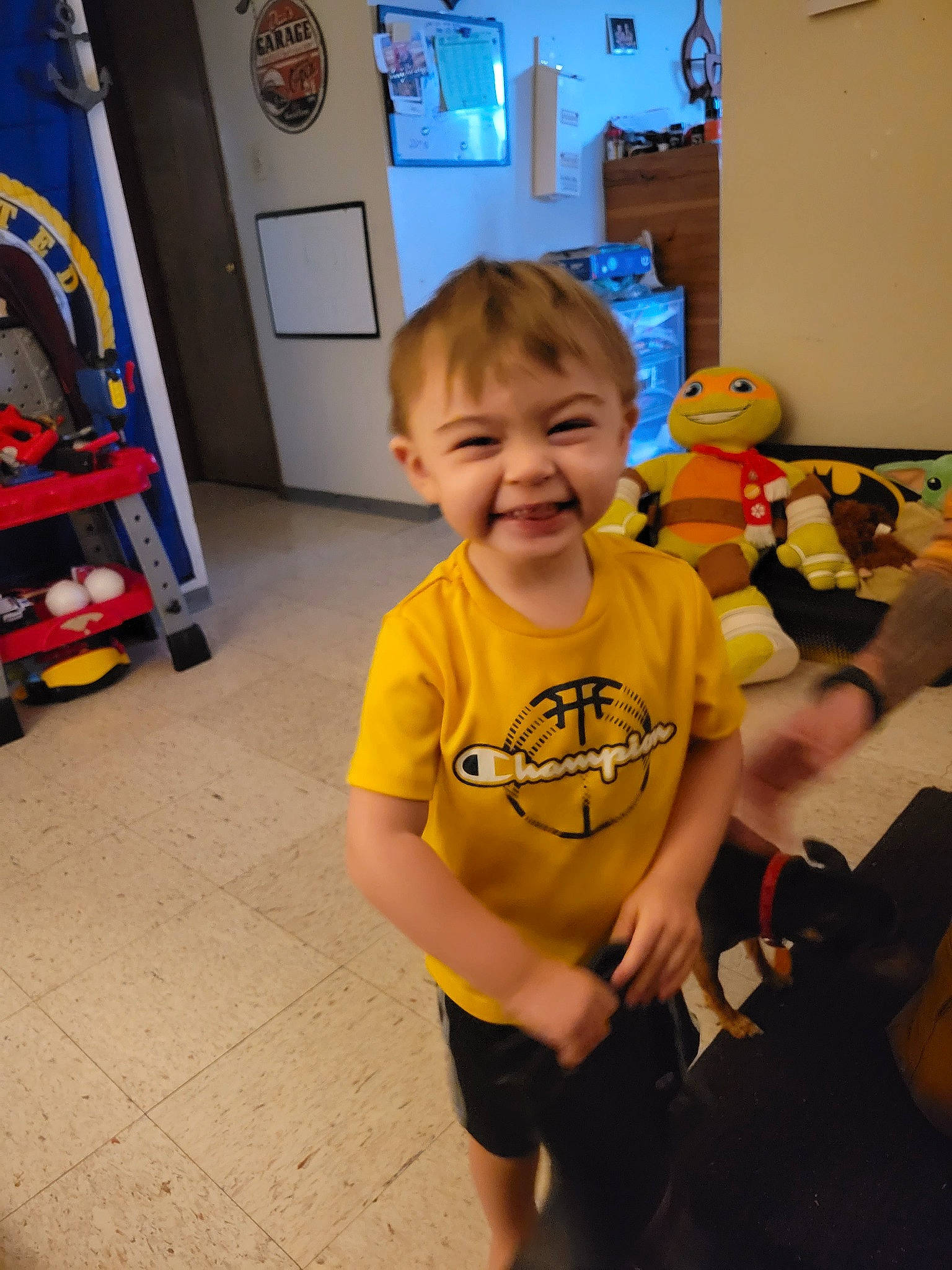 Colson is registered to the contest to win money with this photo: baby, child, floor, flooring, fun, happy, joy, leisure, person, picture_frame, play, room, sandal, shorts, sitting, smile, standing, stuffed_toy, t_shirt, toddler
