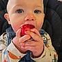 baby, child, blue_eyes, strawberry, fruit, denim_overalls, long_sleeve_shirt, patterned_clothing, high_chair, close_up, cute, hand, face, eating, food, indoor, infant, person, skin, expression