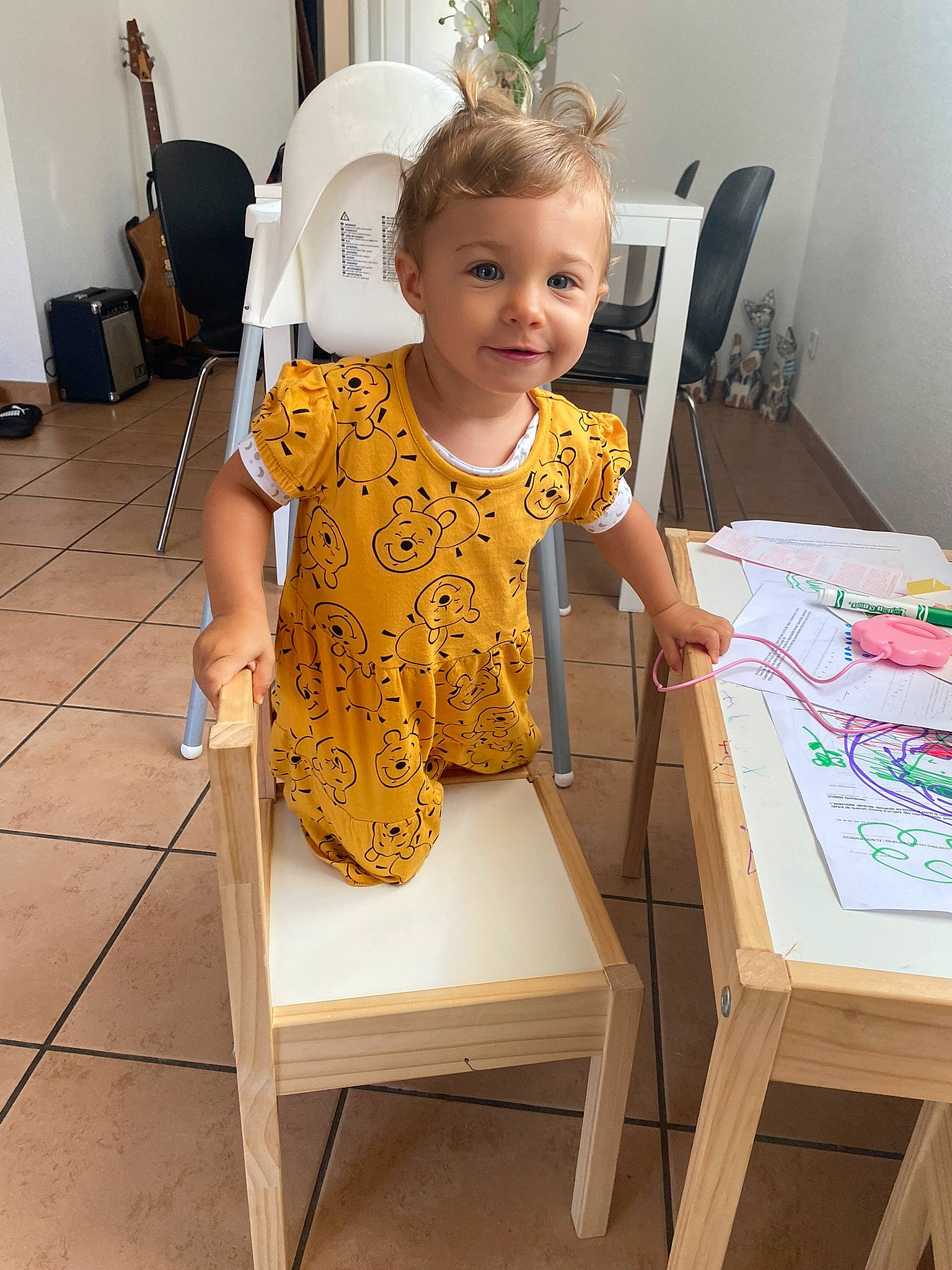 Amélya participe au concours pour gagner de l'argent avec cette photo : baby, baby_toddler_clothing, chair, child, fashion_accessory, flooring, fun, houseplant, joy, lighting_accessory, pattern, person, room, sitting, sleeve, smile, standing, t_shirt, table, toddler