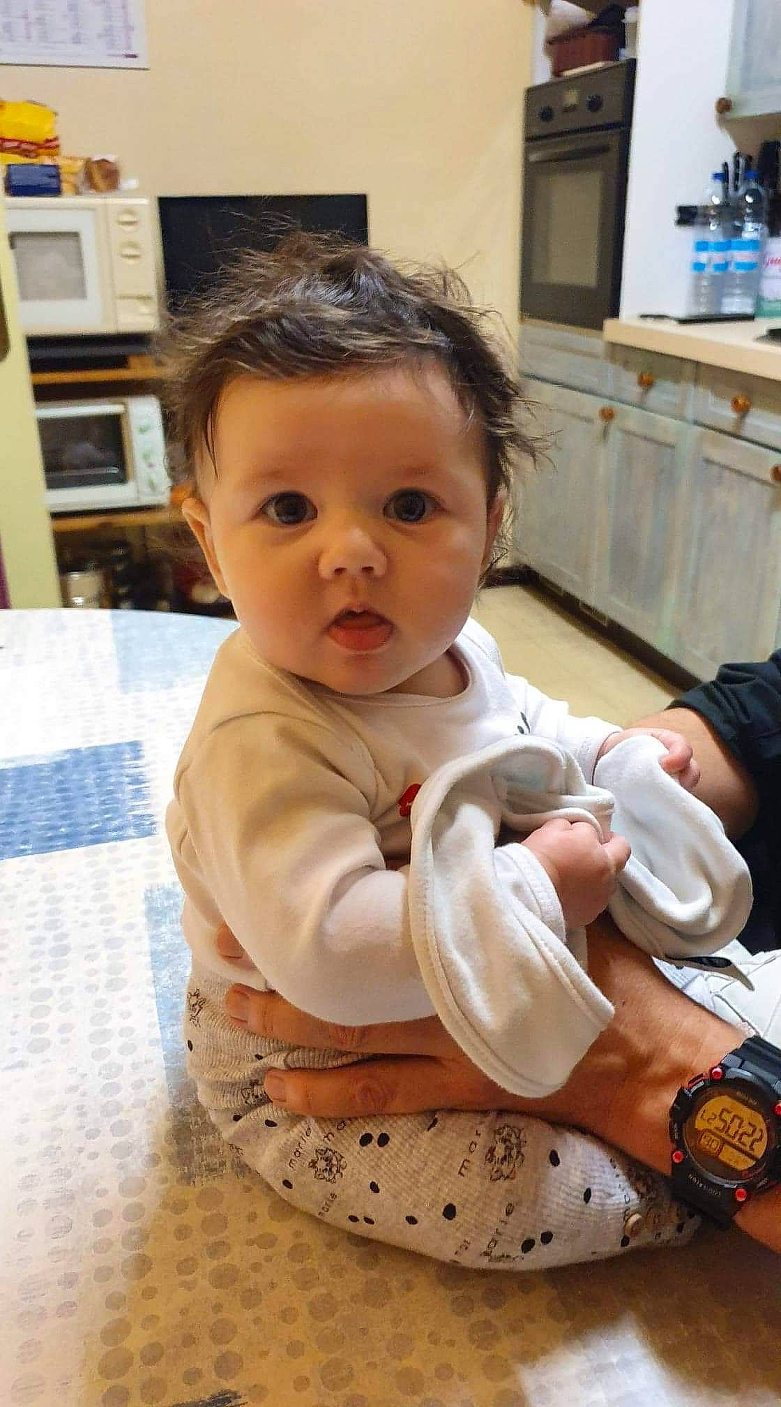 Hanaë a rejoint le concours — aidez-le/la à gagner de superbes lots ! arm, baby, baby_toddler_clothing, bottle, cheek, child, comfort, eye, face, flooring, gesture, happy, iris, person, picture_frame, sitting, skin, sleeve, surprise, toddler