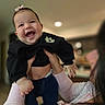 adult, baby, being_held, black_clothing, child, close_up, family, hair_bow, hands, happy, home, indoor, infant, joyful, laughing, long_sleeves, parent, photography, portrait, smiling