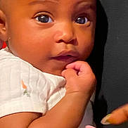 Gerzi is registered to the contest to win money with this photo: baby, infant, face, hand, curly_hair, eyes, skin, clothing, white_shirt, person, holding, nail, manicure, cute, portrait, indoor, close_up, expression, child, human