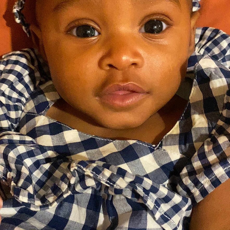 Gerzi joined the competition — help win amazing prizes! baby, background, blue, checkered, child, clothing, cute, dress, expression, eyes, face, headband, infant, lying, pattern, person, portrait, skin, white, young