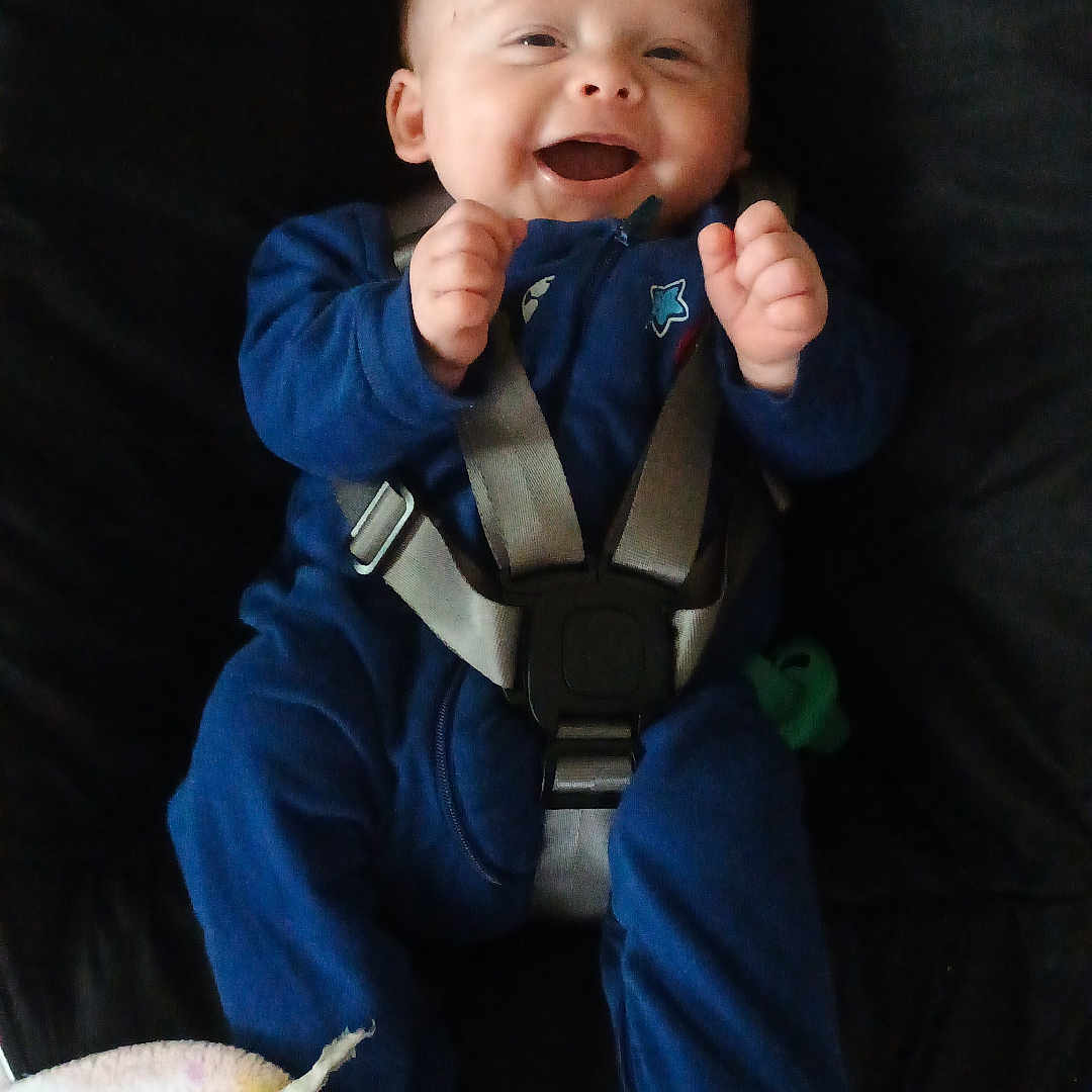 Ryan is registered to the contest to win money with this photo: accessories, baby, bodypart, car, car_interior, carseat, clothing, face, finger, furniture, hand, hat, head, pants, person, photography, portrait, strap, transportation, vehicle