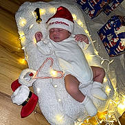 Eithan joined the competition — help win amazing prizes! baby, sleeping, christmas_hat, white_onesie, fairy_lights, fluffy_blanket, candy_canes, red_boots, wooden_floor, holiday, presents, gift_wrap, festive, cozy, indoors, infant, cute, holiday_decor, celebration, peaceful