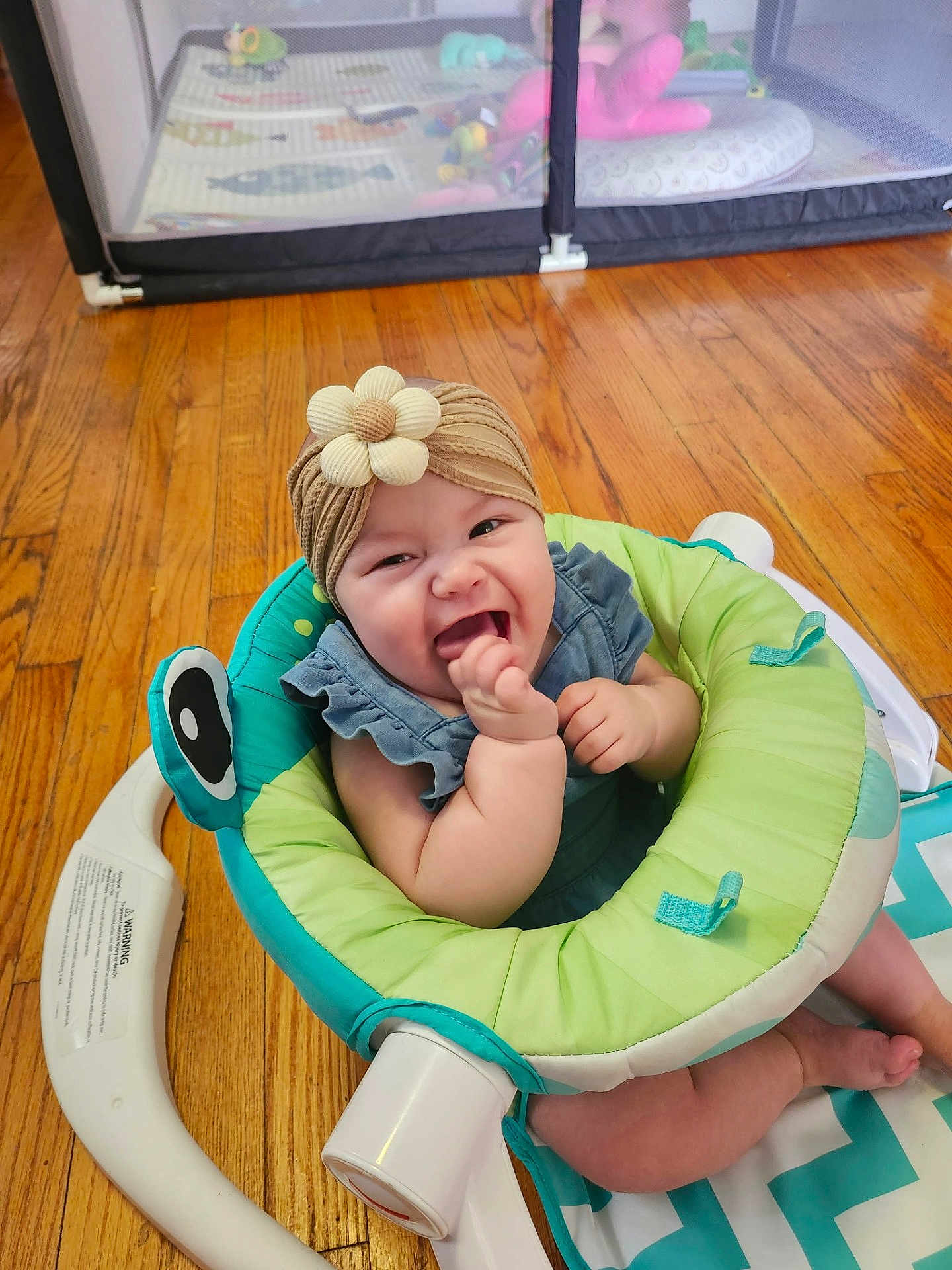 Kendra joined the competition — help win amazing prizes! baby, smiling, headband, flower, baby_seat, wooden_floor, playpen, toes, happy, infant, child, indoor, cute, playtime, blue_clothing, green, white, flooring, toy, home