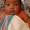 Mckenzie is registered to the contest to win money with this photo: baby, infant, child, portrait, face, eyes, serious_expression, lying_down, blanket, swaddled, orange_clothing, striped_blanket, cozy, indoors, bed, textile, head, hair, closeup, photography