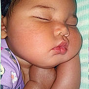 Mckenzie is registered to the contest to win money with this photo: baby, sleeping, infant, portrait, face, curled_up, cheeks, pursed_lips, closed_eyes, peaceful, cozy, blanket, purple_clothing, indoors, close_up, resting, arms, soft_lighting, nap, child