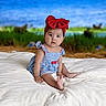 baby, child, girl, blue_dress, red_bow, headband, sitting, blanket, outdoor, grass, nature, portrait, curious, cute, infant, soft_lighting, young_child, human, one_person, expression