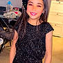 Djenna participe au concours pour gagner de l'argent avec cette photo : child, girl, smiling, sparkly_outfit, black_clothing, bow, long_hair, indoor, dining_table, chairs, floor, cabinet, screen, modern, portrait, happy, person, standing, home, bright