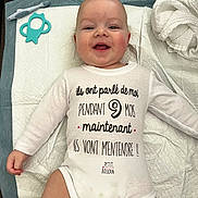 Antoine participe au concours pour gagner de l'argent avec cette photo : baby, infant, smiling, onesie, lying_down, baby_toys, teether, changing_pad, white_clothing, cute, happy, child, face, skin, head, hand, expression, baby_care, indoors, soft_texture