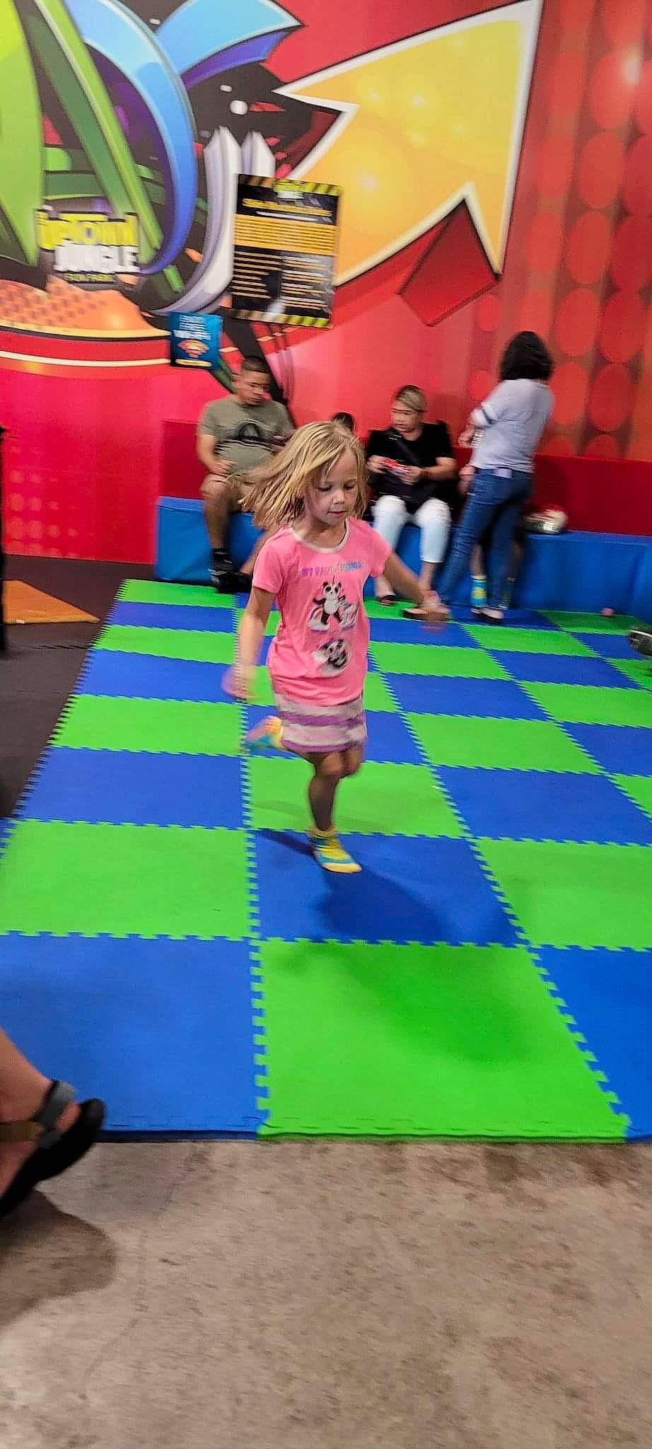 Kelsey is registered to the contest to win money with this photo: blue, bounce_house, carpet, child, electric_blue, entertainment, event, floor, flooring, fun, grass, leisure, magenta, person, play, playground, purple, recreation, shorts, toddler