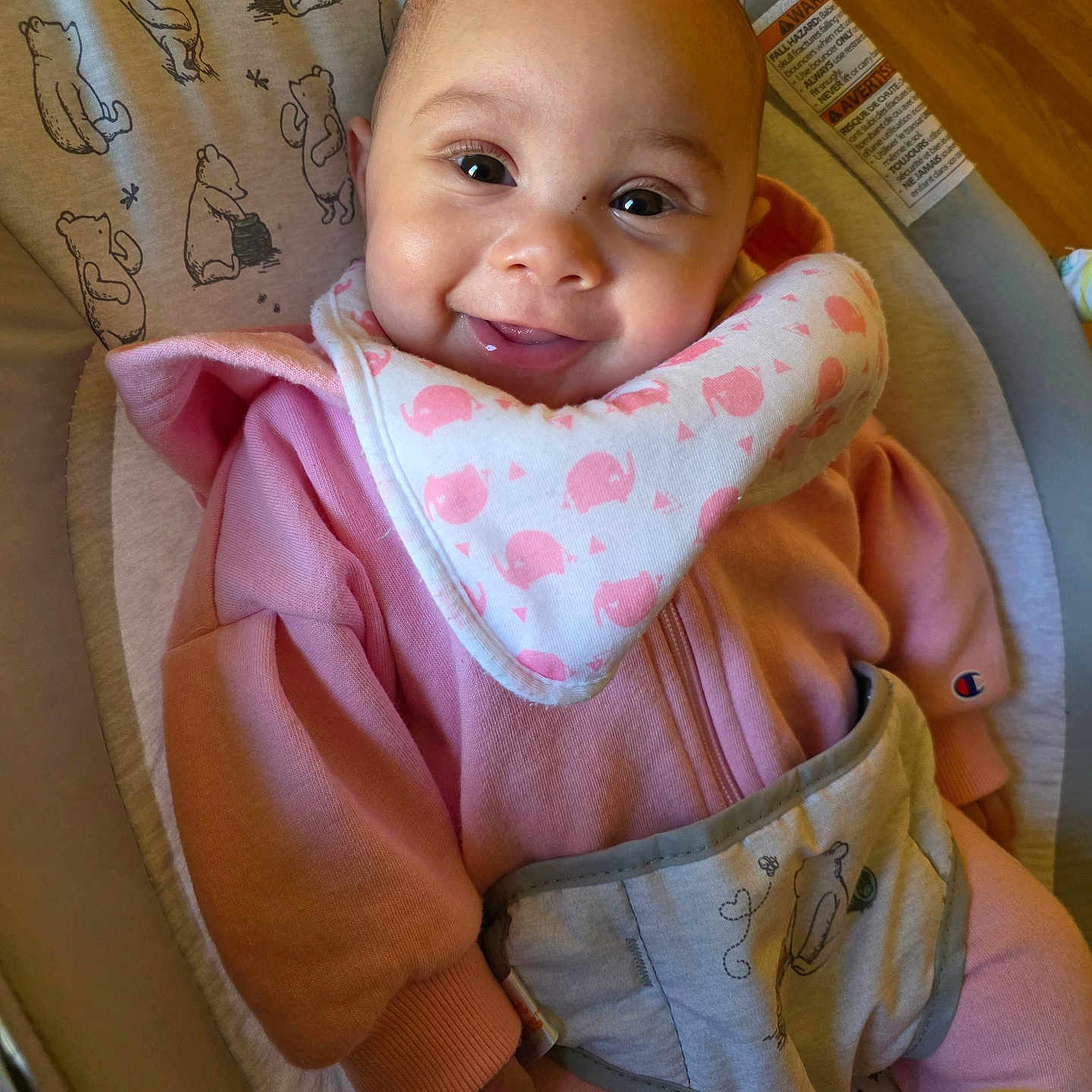 Brynlii joined the competition — help win amazing prizes! baby, infant, smiling, pink_clothing, bib, baby_seat, bear_pattern, happy, cute, child, indoors, portrait, person, cozy, seat, apparel, human, sitting, face, young_child