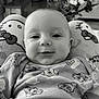 baby, infant, smiling, onesie, cartoon_pattern, plush_cushion, hello_kitty, face, indoor, furniture, flowers, cozy, portrait, child, cute, closeup, home, soft_toys, black_and_white, happy