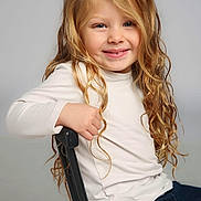 Natalia joined the competition — help win amazing prizes! black_chair, blonde_hair, casual_clothing, child, cream_shirt, curly_hair, cute, dark_pants, friendly, happy, indoors, light_background, long_hair, person, portrait, posing, sitting, smiling, studio, young_child