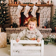 Bjorn is registered to the contest to win money with this photo: baby, carpet, child, christmas_tree, cozy, crate, decorations, festive, fireplace, fur, gifts, happy, holiday, indoor, potted_plants, reindeer, smile, stockings, sweater, wood