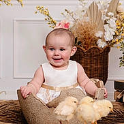 Harley is registered to the contest to win money with this photo: baby, child, dress, chicks, bird, animal, egg, prop, smile, happy, indoor, flower, decoration, basket, cute, portrait, infant, nature, soft, warm_tones