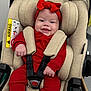 baby, infant, car_seat, red_clothing, red_headband, smiling, child, seat_belt, safety, cute, happy, indoors, person, face, small_hands, car_seat_padding, fabric, head_support, baby_clothes, toddler