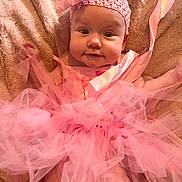 Dorothy is registered to the contest to win money with this photo: baby, pink, tutu, headband, flower, blanket, soft, cute, infant, tulle, clothing, portrait, smile, face, person, lying_down, child, fashion, texture, adorable