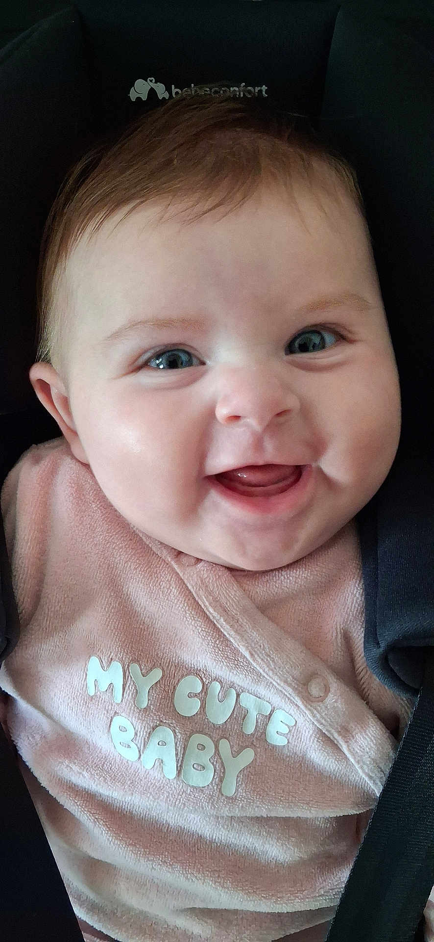 Nina participe au concours pour gagner de l'argent avec cette photo : baby, smiling, infant, pink_clothing, face, car_seat, child, happy, blue_eyes, closeup, cute, soft_texture, seatbelt, apparel, person, portrait, young, baby_girl, clothing, sitting